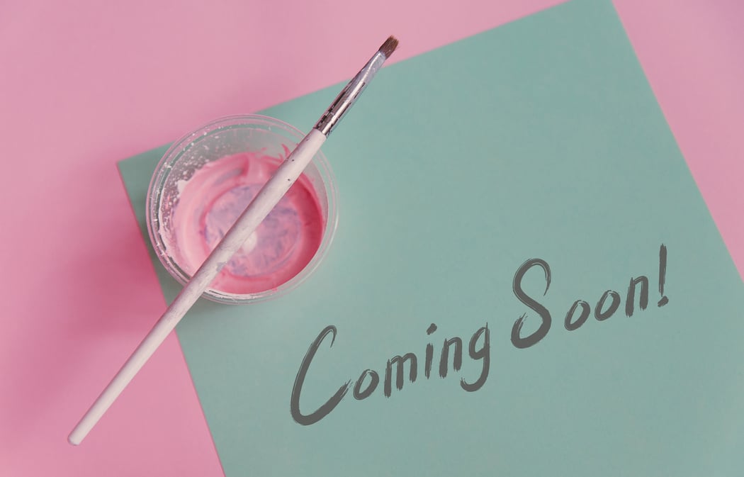 Mint paper on pastel pink background with paintbrush and paint. Minimal concept. Coming soon hand drawn lettering phrase. Copyspace for your text.